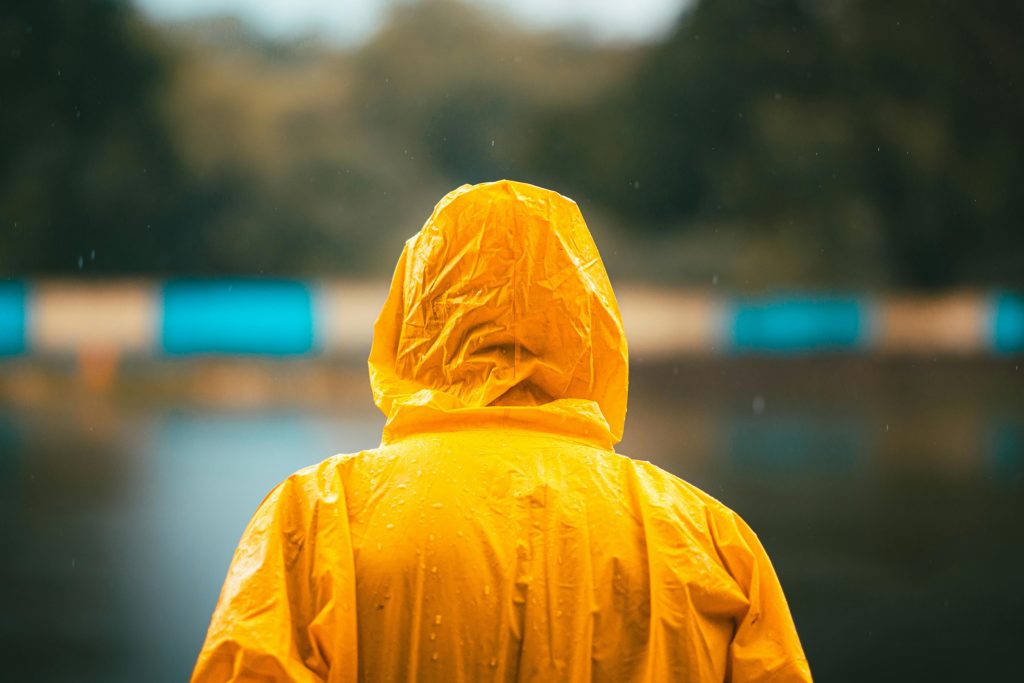 pexels photo 33231026 33231026 Person in a vibrant yellow raincoat standing by a calm lake on a rainy day.