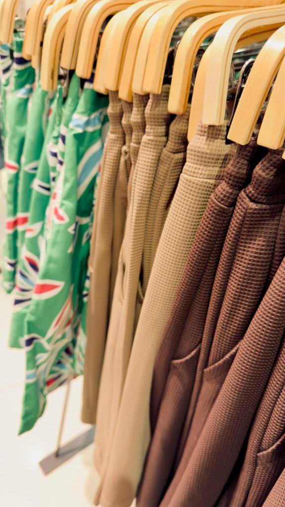 pexels photo 37420546 37420546 Browse a vibrant display of summer clothes on wooden hangers, featuring textures and patterns.