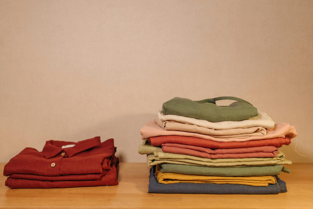 pexels photo 6461395 6461395 Neatly folded colorful clothes on a wooden table, showcasing texture and style.