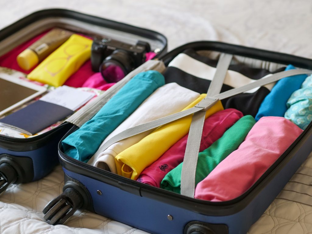 pexels photo 8212229 8212229 Open suitcase neatly packed with colorful clothes and travel essentials.